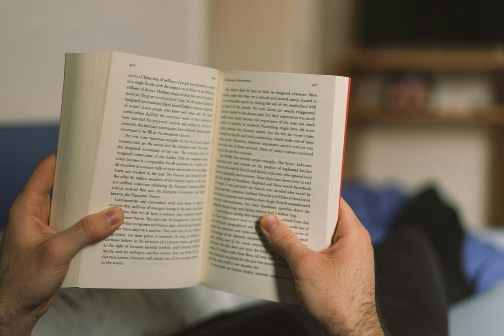 leitura Imagem de uma pessoa segurando um livro aberto nas mãos estando deitada