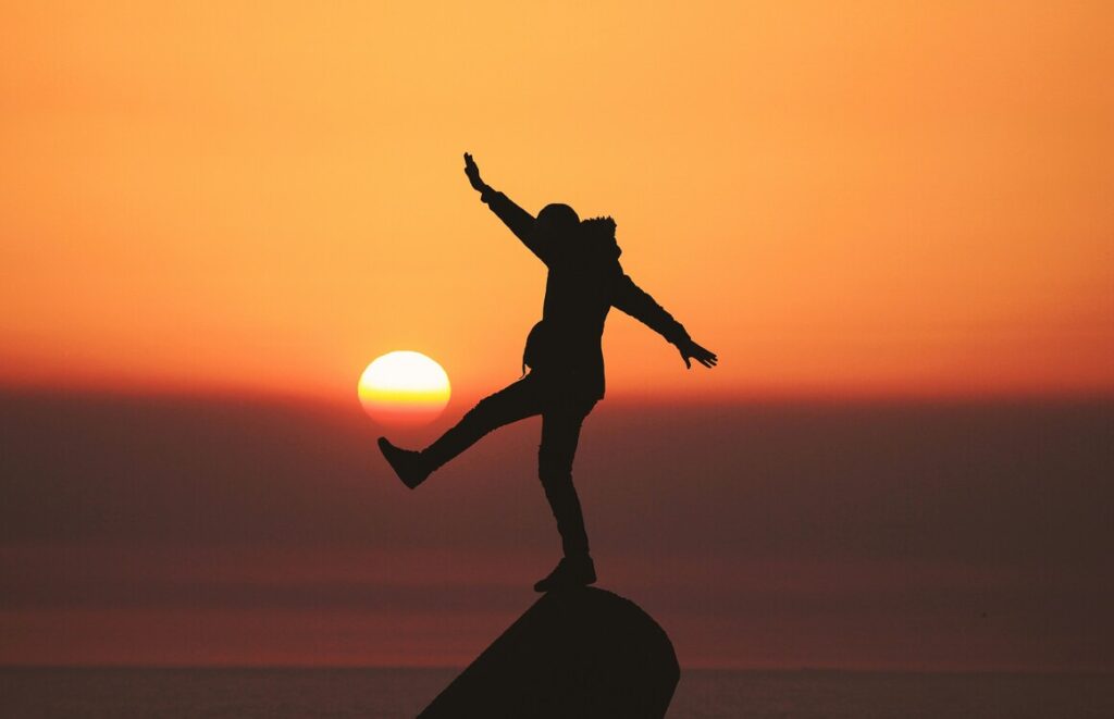 se-liberte Imagem de um homem fazendo uma pose de braços aberto e ao fundo um por do sol
