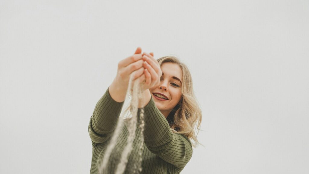 Imagem de menina feliz segurando a areia da praia